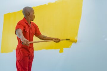a man painting a wall with yellow paint